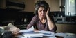 © Justlight - distressed middleaged woman sits at her kitchen table, piled high with medical bills, insurance paperwork, and prescriptions. Her face reflecting her frustration and fear.