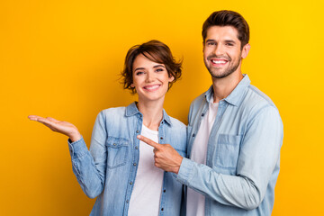 Fototapete - Photo of cheerful people wife husband dressed trendy denim clothes arm hold empty space special offer isolated on yellow color background