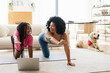 © Maria Vitkovska - Smiling African American little daughter and mother on yoga mat doing yoga exercises at home