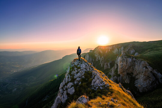 A man who hikers enjoys a break look at the top of the mountain at sunset adventure travel.