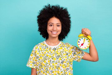 Canvas Print - Photo of cheerful cute girl wear stylish print clothes hand hold watch early morning wakeup school isolated on cyan color background