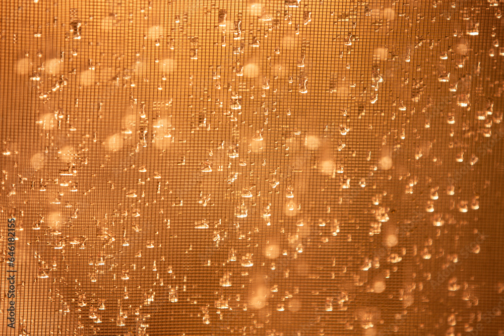Water drops on a glass surface in golden tone. Abstract background ...
