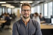 © NikoG - Smiling portrait of a happy young caucasian man working for a modern startup company in a business office