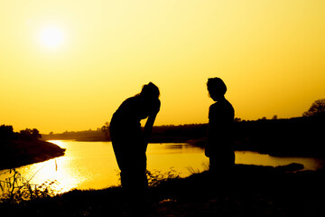 Silhouette of a family comprising a father, mother and two children happy family the sunset.Concept of friendly 