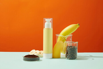 Wall Mural - A yellow pump bottle unlabeled with lab glassware container bananas, banana slices, coffee beans and coffee powder on orange background. Minimal concept for organic cosmetic