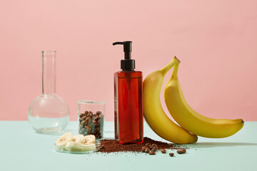 Wall Mural - Mockup of cosmetic bottle container shampoo or shower gel decorated with bananas and coffee beans, coffee powder on color background. Lab concept for advertising products