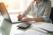 © BOONJUNG - Closeup shot of businesswoman using a calculator and laptop in an office.