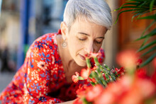 Woman Wearing Red Dress Smelling Flowers