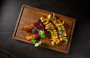 Canvas Print - Horizontal top view of juicy BBQ ribs served with spiral potatoes and mushrooms, beautifully presented on a wooden board against a minimalist black backdrop. Perfect for a pub menu