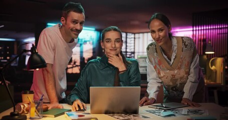 Poster - Diverse Teammates in a Creative Office Using Laptop Computer, Looking at Camera and Smiling. Posing Shot of Three Talented Young Business People Gathered Around a Desk to Brainstorm Innovative Ideas