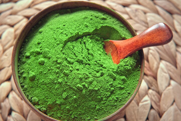 Wooden spoon with powdered matcha tea in a bowl spinning on natural background. Matcha powder. Top view, Closeup. Finely ground green powder. Japanese culture. Healthy eating with high antioxidants.