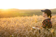 © scharfsinn86 - Woman farmer working with laptop on wheat field. Smart farming and digital agriculture