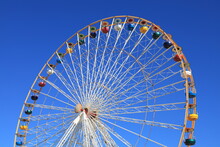 Ferris Wheel Featuring Colourful Seating Pods Against Backdrop Of Blue Sky