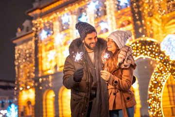 couple celebrating new year outdoors holding sparklers and hugging