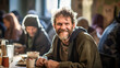  Happy homeless age of 30 sits at a table with other homeless in a social centre with meal in evening