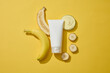 Flat lay of a glass petri dish filled with cream texture, banana slices and an unlabeled tube. Banana (Musaceae) contains vitamins A and C. Branding skin care mockup