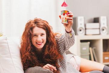 Redhead celebrates on sofa, mixing comfort, festivities