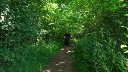 Wall Mural - A photographer standing behind a tripod in a forest