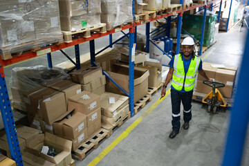 Multiracial warehouse worker pulling hand pallet truck loading cardboard package boxes stacking in storehouse. Foreman moving merchandise by hand lift pallet jack. Delivering goods, cargo transport.