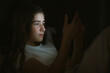 © Natalia - child teenager girl lies in bed in evening or at night and looks into phone. mobile addiction.