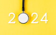 Leinwandbild Motiv The stethoscope with number 2024 on yellow background. Happy new year for health care and calendar cover.