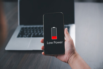 Close up man's hands using smart phone battery low charge battery screen, Businessman holding a smartphone  Low battery warning on a mobile phone. Need to connect the charger to the smartphone icon