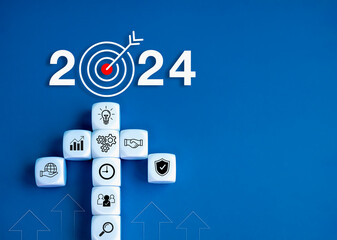 Wall Mural - 2024 leadership business goal concept. 2024 year number with target icon and white cube block arranged as an arrow shape with business strategy element symbols on blue background with copy space.