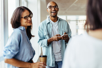 Poster - Business man standing with his colleagues and using a mobile phone