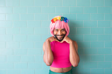 Smiling Man Wearing Pink Wig Standing In Front Of Wall
