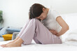 © Pormezz - Close-up woman feeling stomach pain from cycle period on the bed at home.