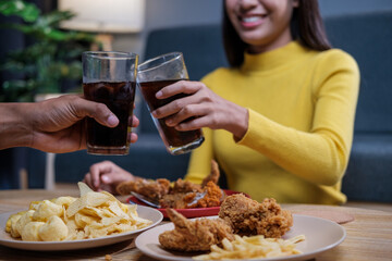 Asian man and woman couple happily eating together inside their home celebrating the weekend.