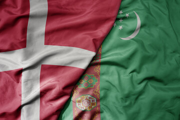 big waving national colorful flag of denmark and national flag of turkmenistan .