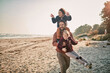 © Marko Geber - Happy young father taking his kids for a walk on a sandy beach during winter