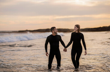 Wall Mural - Happy Couple Holding Hands While Walking On The Beach Together