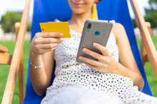 Anonymous Happy Woman With Credit Card And Smartphone On Deckchair