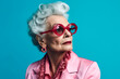 © ADDICTIVE STOCK - Generative AI illustration of elderly fashionable female with wrinkled face wearing sunglasses and earrings looking away while standing against blue background