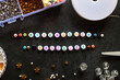 Friendship bracelet letter beads and various other jewelry making supplies on dark background. Top view.