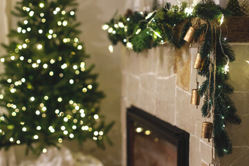 atmospheric christmas eve. stylish decorated christmas tree with lights and modern decor on fireplac