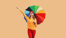 Autumn Color Style Outfit, Beautiful Happy Cheerful Young Woman Holds Colorful Umbrella Enjoys New Season In French Beret Hat, Yellow Sweater On Beige Studio Background