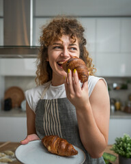 Wall Mural - One adult caucasian woman stand in the kitchen with fresh croissant