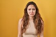 Young hispanic woman standing over yellow background depressed and worry for distress, crying angry and afraid. sad expression.