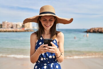 Poster - Young blonde woman tourist wearing summer hat using smartphone at beach