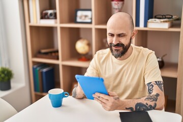 Poster - Young bald man using touchpad sitting on table at home