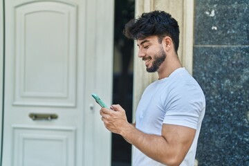 Poster - Young hispanic man smiling confident using smartphone at street