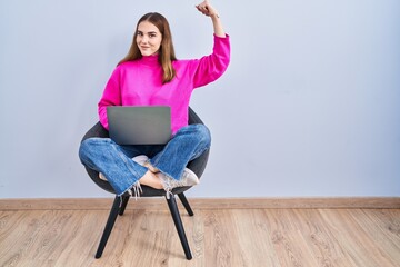 Wall Mural - Young hispanic girl working using computer laptop strong person showing arm muscle, confident and proud of power