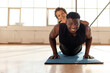 © Богдан Маліцький - african american man with his son goes in for sports in the gym, dad does push-ups from the floor with his son