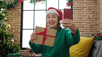 Sticker - Mature hispanic woman with grey hair taking a selfie picture sitting on the sofa at home