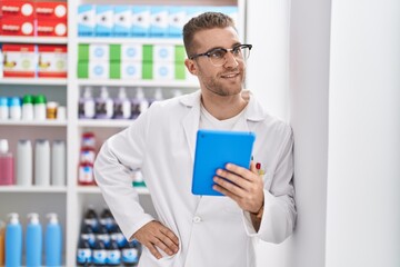 Sticker - Young caucasian man pharmacist using touchpad working at pharmacy