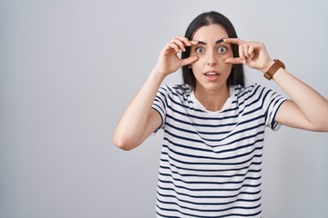 Canvas Print - Young brunette woman wearing striped t shirt trying to open eyes with fingers, sleepy and tired for morning fatigue