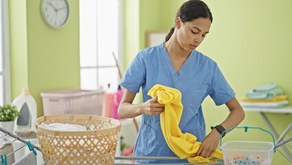 Poster - African american woman professional cleaner hanging clothes on clothesline at laundry room